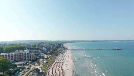Aerial-view-of-beach-tourist-destination-coastline-on-sunny-day,-Baltic-sea,-Scharbeutz,-Germany,-dolly-in